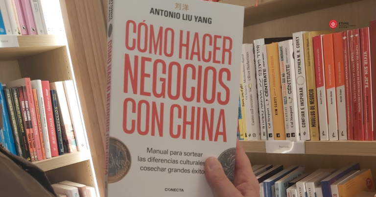 Una persona sostiene el libro “Cómo hacer negocios con China”, de Antonio Liu Yang, frente a una estantería llena de títulos de empresa y comunicación. En la portada se lee: “Manual para sortear las diferencias culturales y cosechar grandes éxitos”.