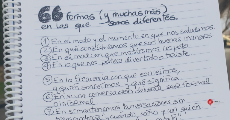 otografía de un cuaderno de espiral abierto, con hojas de líneas y texto escrito a mano en tinta negra. En la parte superior se lee el título “66 formas (y muchas más) en las que somos diferentes”. Debajo aparece una lista numerada con ejemplos de diferencias culturales relacionadas con la comunicación, el trato, el tiempo y la toma de decisiones. El cuaderno está sostenido al aire libre, con un fondo desenfocado.